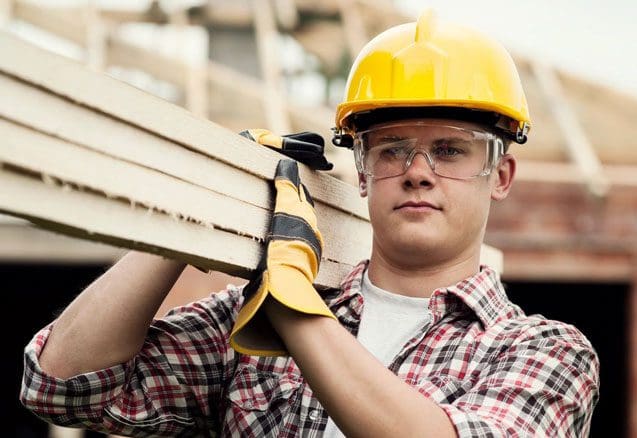 A man in yellow hard hat holding wood.